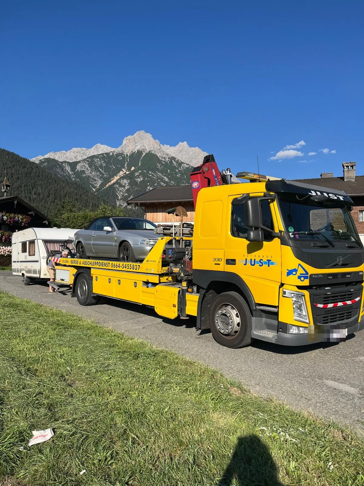 Gelber Abschleppwagen von Autohaus Just vor der Bergkulisse